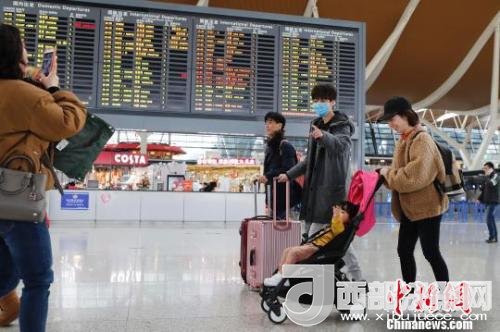 旅客帶著孩子前往辦票柜臺辦理登機(jī)手續(xù)。　殷立勤 攝