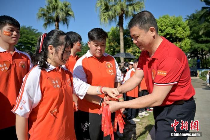 資料圖：廣西華僑實驗高中的教師為高三學(xué)子系上紅絲帶，盼望學(xué)子高考必勝。 俞靖 攝